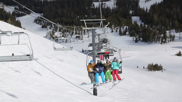 Four snowboarders riding up ski lift