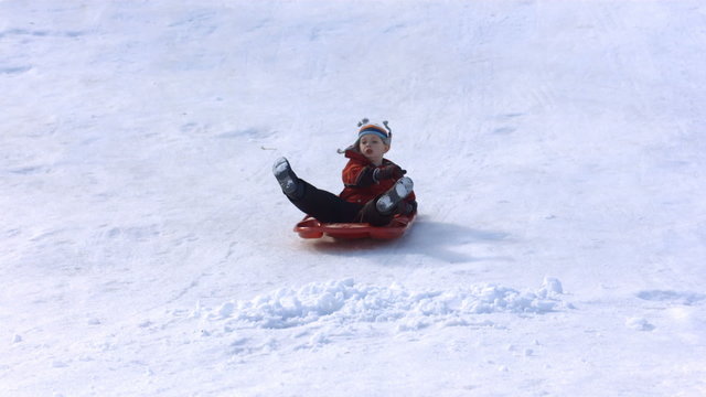 Young boy on fast sled hits pile of snow
