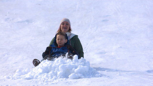 Slow motion mom sledding with son