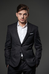 Confudent young businesssman in black suit and white shirt