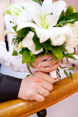 Hands with wedding rings on bridal bouquet