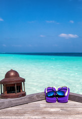 Flip Flops mit Sonnenbrille auf einem Holzsteg in den Malediven