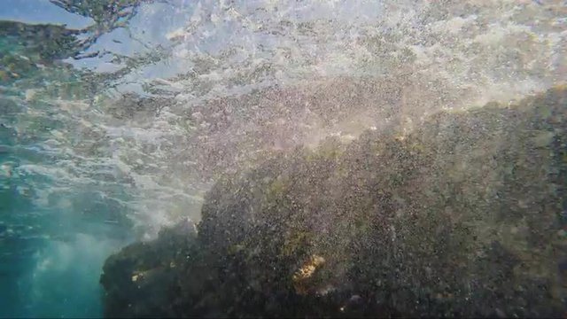 Surf under water, waves breaking on the rocks