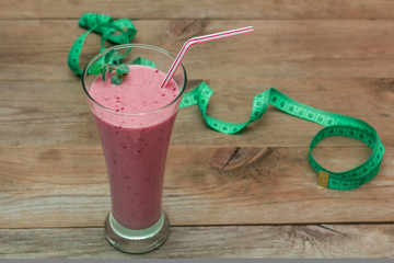 glass of fruit smoothie and a measuring tape