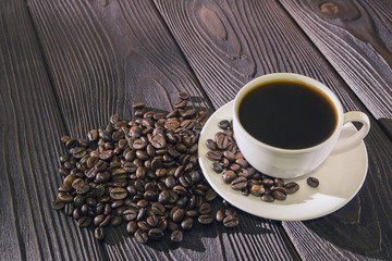 Cup of coffee on wooden background with coffee beans