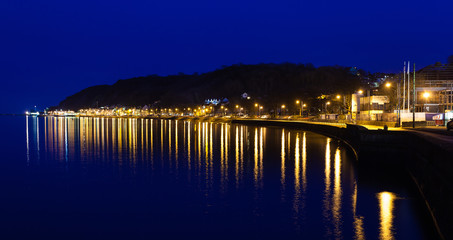 The village lights of Mumbles reflect in the high tide of Swansea Bay