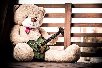 Big fluffy teddy bear with a guitar.