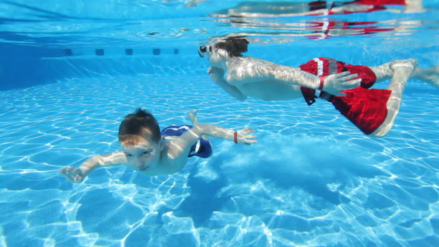 Young boys swimming underwater in pool