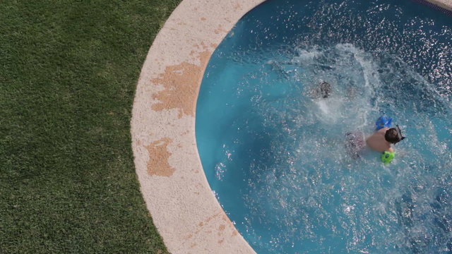 Two young boys jump into pool, overhead view