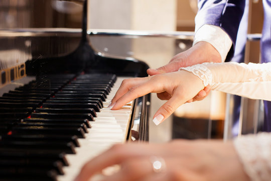 newlyweds play on grand piano keys