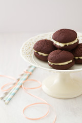 Chocolate whoopie pies with buttercream filling on cake stand