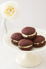 Chocolate whoopie pies with buttercream filling on cake stand