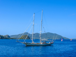 Sailboat navigates in the waters of the Archipelago of Les Saintes, Guadeloupe in the blue carribean sea.