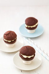 Three chocolate whoopie pies with buttercream filling on cake stand