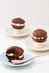 Three chocolate whoopie pies with buttercream filling on cake stand