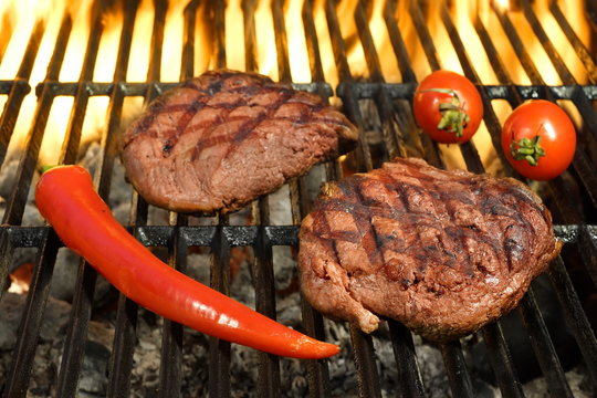 Two Sirloin Beef Steak On The Hot Flaming BBQ Grill