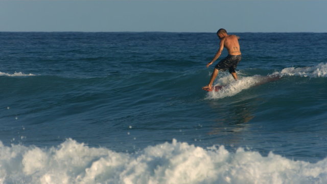 Long board surfer hangs ten, slow motion