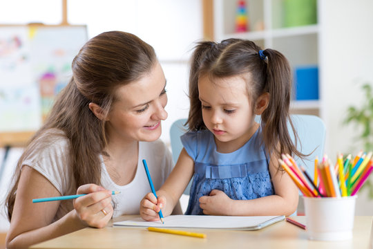 Mother looking how her child daughter drawing a picture