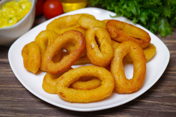 deep fried calamari with sauce and salad on a wooden background