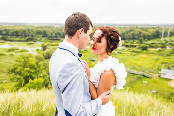 Bride and groom at wedding Day walking Outdoors on spring nature. Happy Newlywed  embracing in green park. 