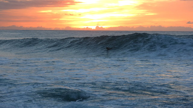 Surfer wipes out at sunset, slow motion