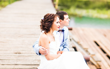 Beautiful young wedding couple sitting on the pier