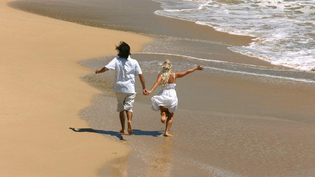 Young couple running on beach, slow motion