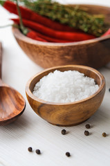 Salt, pepper, chili and thyme in bowls on white rustic wooden table, Vertical orientation