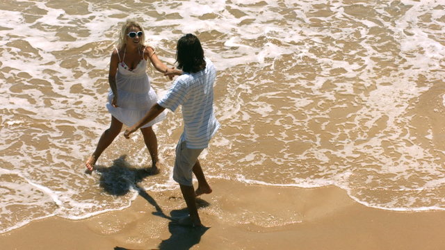 Couple dancing in ocean surf, slow motion