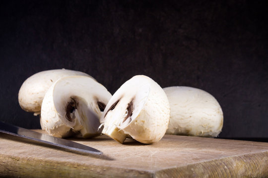 Champignon mushrooms on cutting board and dark background 