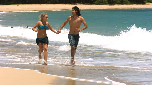 Young couple running on beach, slow motion
