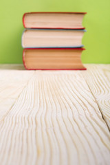 Stack of hardback books, diary on wooden deck table and green background. Back to school. Copy Space. Education background