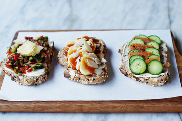 bruschettas with red fish and a cucumber, banana with peanut paste and almonds, tomato with a cucumber, bruschettas on a wooden board, tasty food 