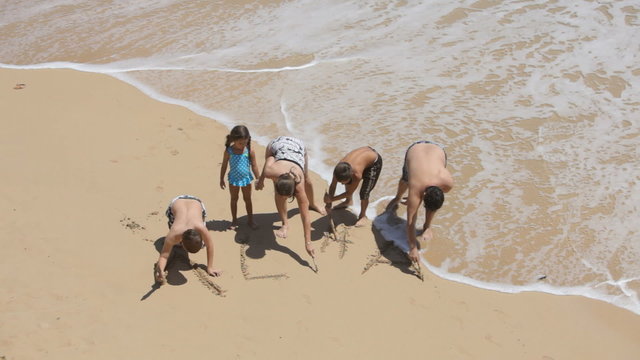Family writes ALOHA in sand at beach