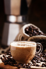 Coffee with milk, coffee maker, coffee beans, dark toned image,