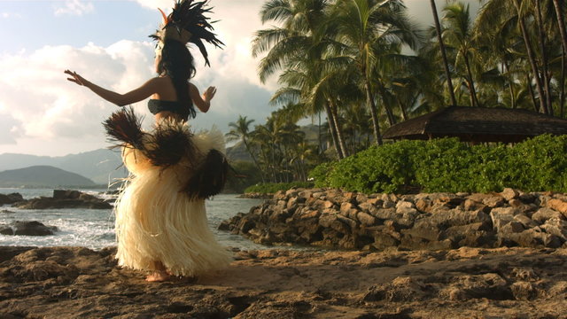 Polynesian dancer performs along rocky coastline, slow motion