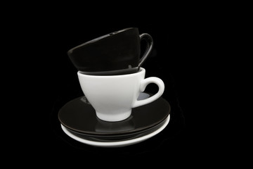 Black and White coffee cups. Two stacked black and white coffee cups and saucers. Isolated on a black background