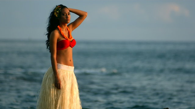 Polynesian woman stands by ocean waves