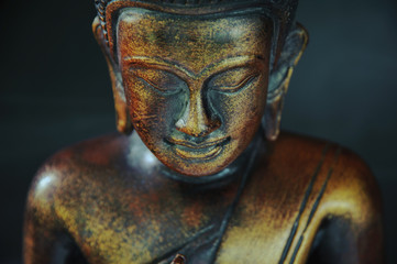Fototapeta na wymiar Wooden bronze buddha on black blurred background