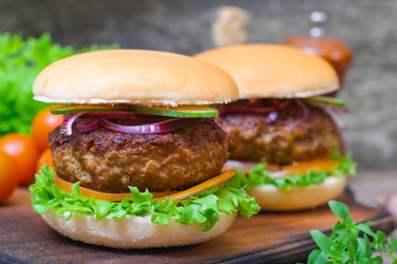Juicy burgers hamburger with a big beef cutlet, tomato, lettuce and onion on wooden background