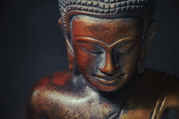 Fototapeta na wymiar Wooden bronze buddha on black blurred background