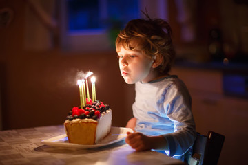 Little kid boy blowing candles on birthday cake