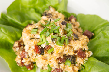 Scrambled eggs with sausage and spring onion on lettuce leaves