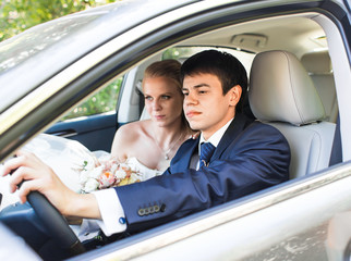 Bride and groom inside a  car. They are happy.