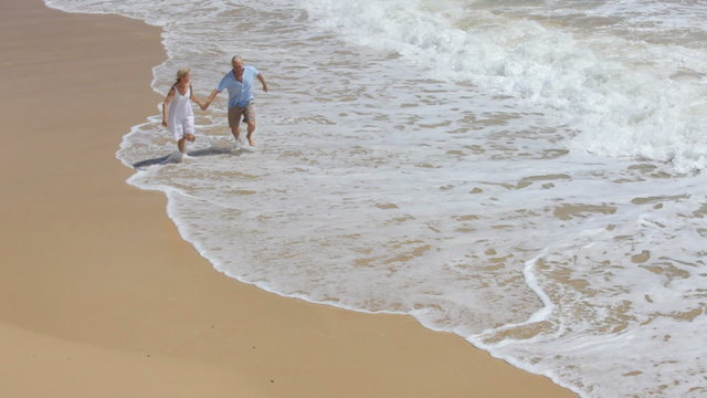Senior couple run on tropical beach