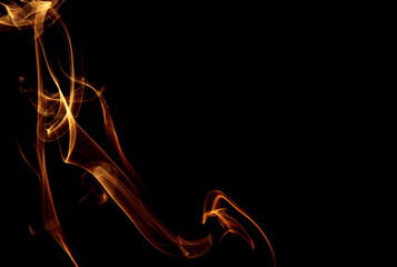 Golden trail of smoke on a black background, abstraction.