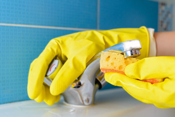 Cleaning - cleaning bathroom faucet with detergent in yellow rubber gloves