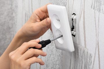 hands installing a wall power socket