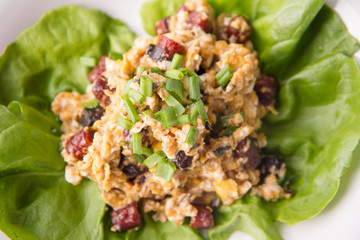 Scrambled eggs with sausage and spring onion on lettuce leaves
