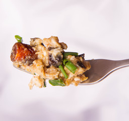 Scrambled eggs with sausage and spring onion on a fork